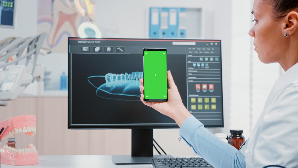 woman working as dentist with green screen smartphone oral care office dentist holding mobile phone with mockup template isolated background teethcare dentistry